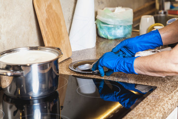 Hands in blue gloves put spoon on plate in kitchen