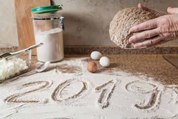 2019. hands hold the dough. Flour and eggs lie on the tabletop