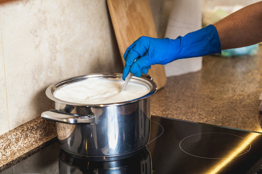 Blue glove hand stirring milk in pan