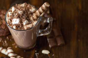 Cup of cocoa with marshmallows and chocolate chip cookies on dark wooden background. Top view