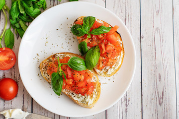 Traditional toasted Italian tomato bruschetta with spice and basil on light wooden background. Top view vith copy space - obrazy, fototapety, plakaty