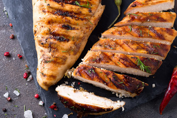 Grilled chicken fillets on slate plate on Gray concrete background. Healthy diet food concept, flat...