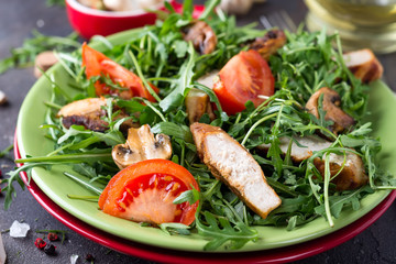 Close-up on a salad with chicken and tomato on green ceramic plate in a stone table. Healthy diet food concept,