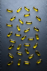 Omega 3 Gelatin Capsules Scattered On A Black Slate Table. Fish Oil, Vitamins, Pills. Medical Series. Close Up. Top View.
