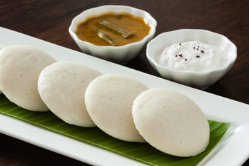Indian idly with chutney and sambar - Fresh steamed Indian Idly (Idli / rice cake) arranged on banana leaf lined plate. Served with coconut chutney and sambar. Natural light used.