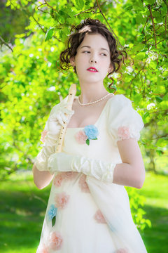 Happy woman musician in a beautiful long white dress with a flute in hand