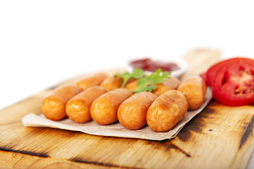 Fried sausages and fresh tomato, ketchup, coriander on the wood plate, isolated white background.