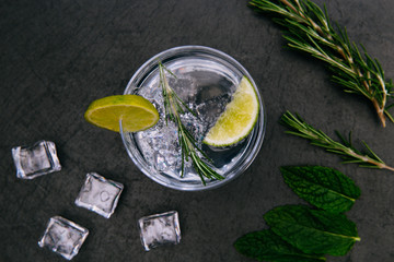 Gin tonic cocktail drink with ice glass dark background