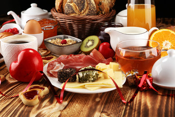 breakfast on table with bread buns, croissants, coffe and juice on valentines day.