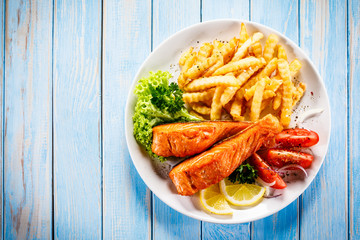 Fried salmon, French fries and vegetables