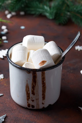 Winter hot drink close up. Hot chocolate or cocoa with marshmallow and spices on dark stone background.