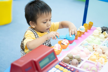 A toddler boy playing ice cream parlor toys