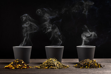 trois tasses de thé derrière trois petit tas de feuille de thé