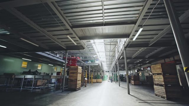 Walking through a factory warehouse with crates and pallets for storage of supplies.