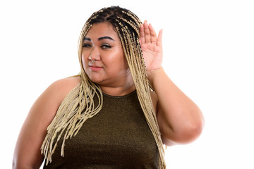 Studio shot of young fat Asian woman listening