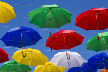 Soaring colored umbrellas against a blue sky