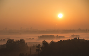Bright beautiful dawn, the sun rises over the city, the light passes through the fog