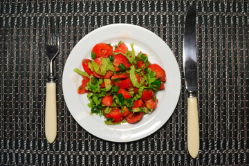 bright appetizing salad of tomatoes and herbs on a white plate on top