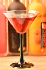 Cocktail glass with a drink in the bar with bottles on a light background