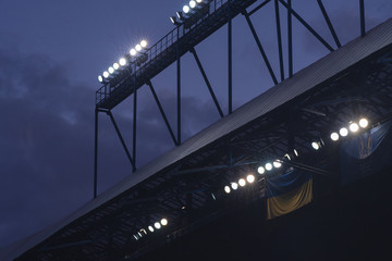 Floodlight mast with some lights on against dark blue sky. Stadium lights.