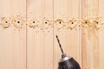 drill with a borer on the bars with holes and sawdust
