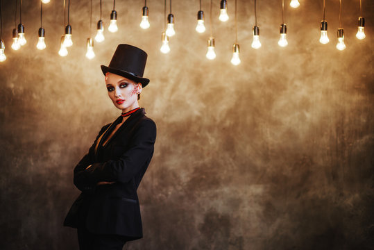 A girl in stylish top hat with skull make up. Halloween party.