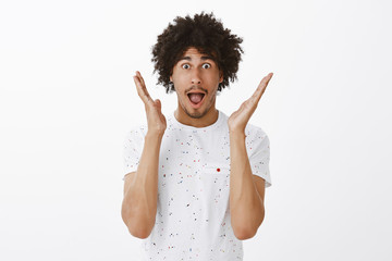 Man describing feelings to friends after amazing match he attended. Portrait of impressed and amazed good-looking hispanic male with moustache and curly hair, gesturing palms and dropping jaw