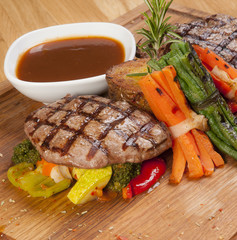 grilled beef steak on wooden board with sauce
