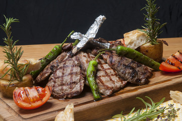 mixed meat grill on wooden platter with vegetables