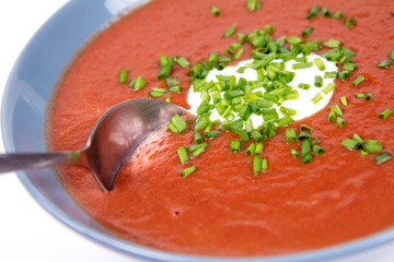 Beetroot cream soup decorated with yogurt and chives being eaten with a spoon