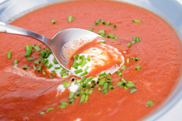 Beetroot cream soup decorated with yogurt and chives being eaten with a spoon