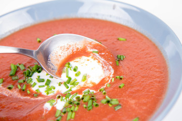 Beetroot cream soup decorated with yogurt and chives being eaten with a spoon