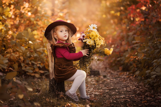 Little cute girl in red hat holding a  Beautiful bouquet of bright and colorful flowers in in autumn forest. Retro concept