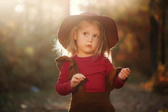Little cute girl in red hat in autumn forest, looking surprised. Retro concept