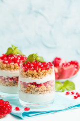 Pomegranate parfait - sweet organic layered dessert with granola flakes, yogurt and ripe fruit seeds.