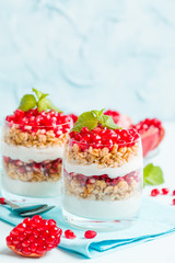 Pomegranate parfait - sweet organic layered dessert with granola flakes, yogurt and ripe fruit seeds.