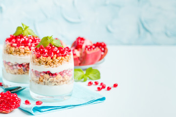 Pomegranate parfait - sweet organic layered dessert with granola flakes, yogurt and ripe fruit seeds.
