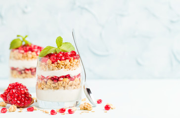 Pomegranate parfait - sweet organic layered dessert with granola flakes, yogurt and ripe fruit seeds.