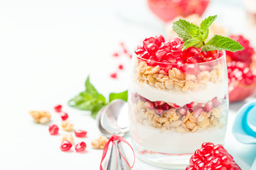 Pomegranate parfait - sweet organic layered dessert with granola flakes, yogurt and ripe fruit seeds.