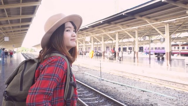 Slow motion - Happy Asian woman waiting the train at train station for travel in summer. Travel Thailand concept.