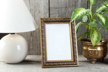 Empty brass picture frame on wooden background.