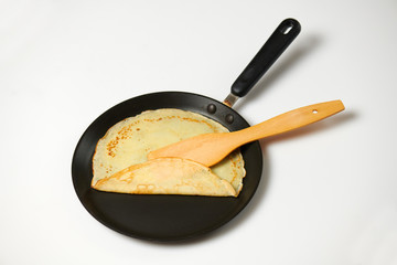 Crepe closeup, thin pancake on a frying pan, white background