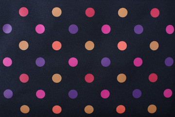 Close-up seamless texture background of colorful polka dots pattern on a black textile background.