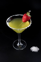 yellow cocktail with strawberry and salt skewer around on black background