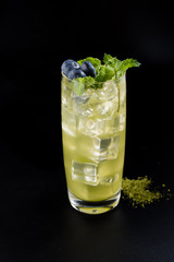 cocktail with ice cubes, mint, blue berries, and whasabi on the back background