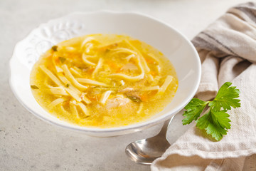 Homemade chicken noodle soup in a white plate, white background.