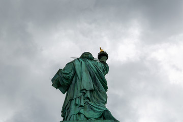 New York City / USA - AUG 22 2018: The statue of liberty back view in cloudy sky