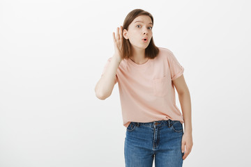 Curious talkative attractive woman with short hair in t-shirt, bending left while holding hand near...