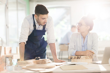 Female expert and male engineer discussing characteristics of materials for cabinetmaking