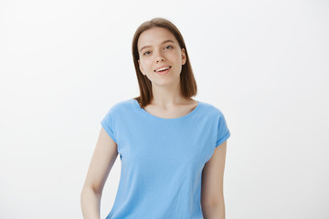 Obraz premium Charmed attractive cute girl with fair hair and clean skin, gazing fascinated at camera and smiling broadly, being like in dream after seeing love of her life, standing pleased over grey wall